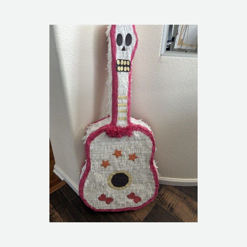 A guitar piñata in white and pink with orange stars