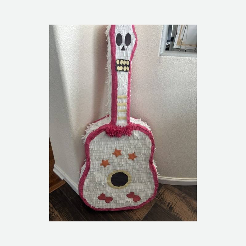 A guitar piñata in white and pink with orange stars